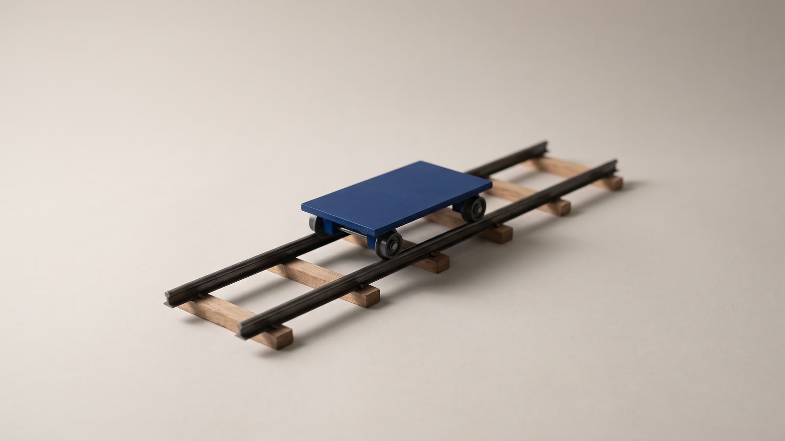 A short section of camera dolly track with a small wheeled platform resting on the rails