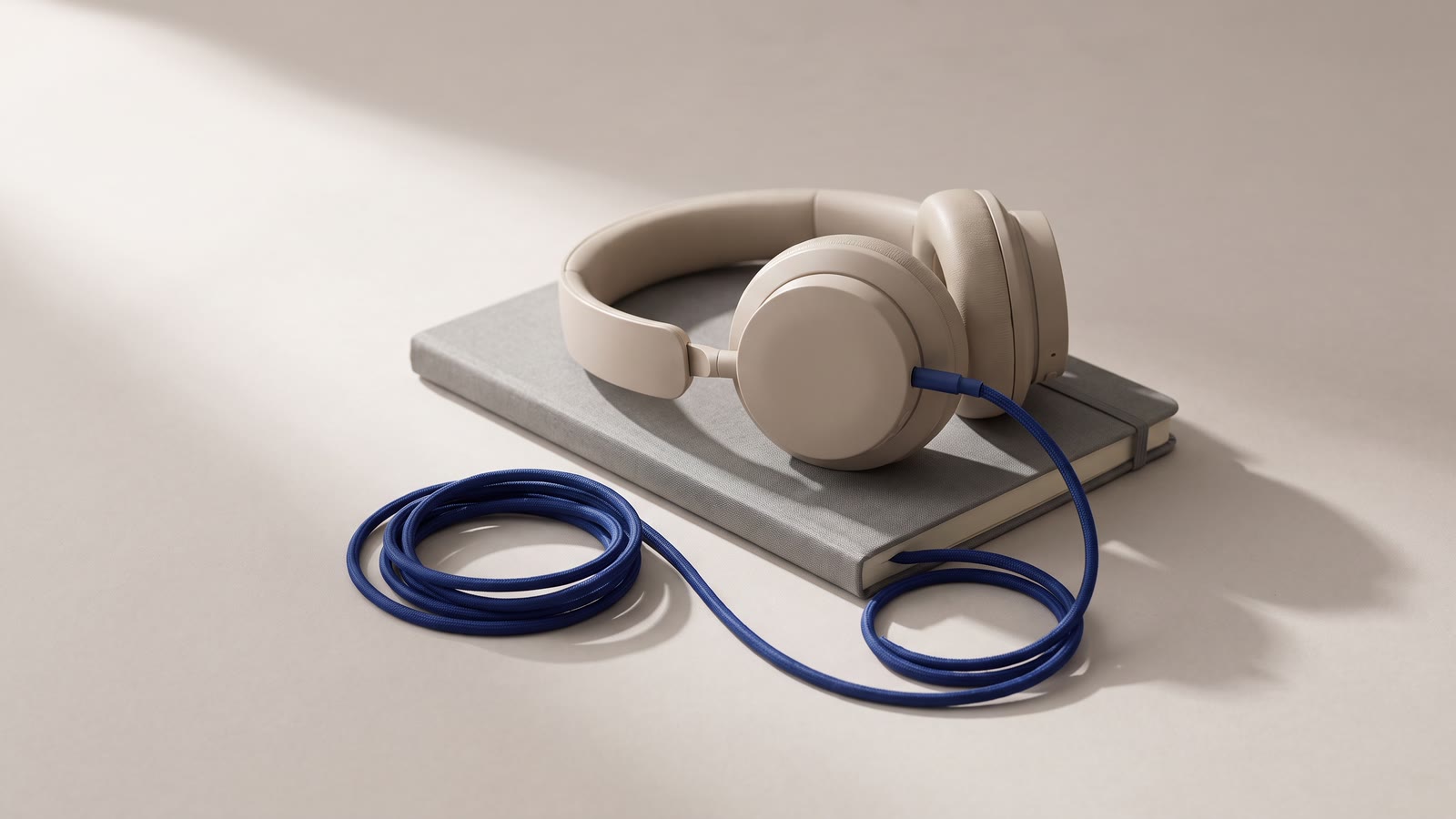Headphones resting on a notebook with a coiled cable