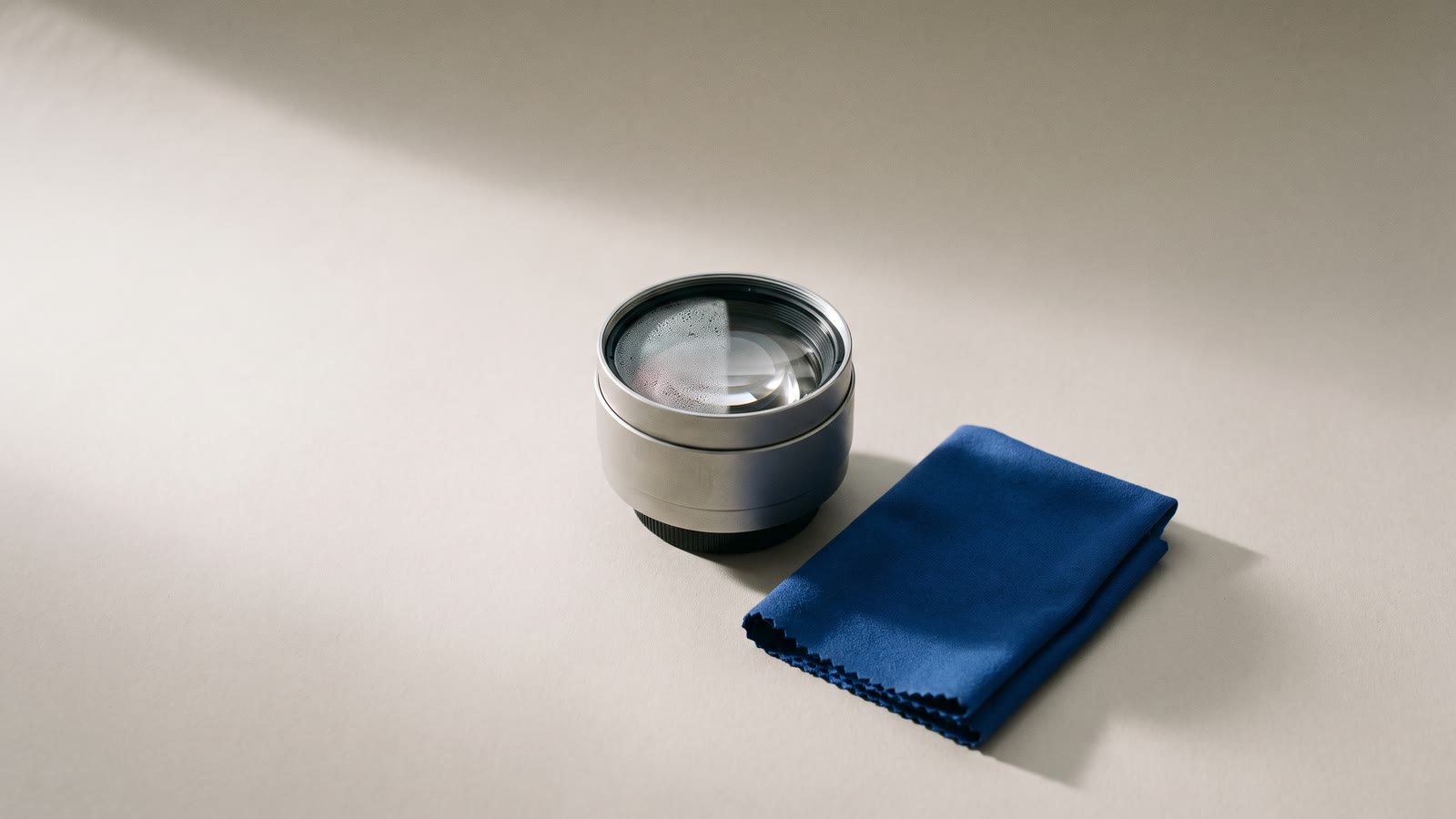 A camera lens half fogged and half clear beside a cloth