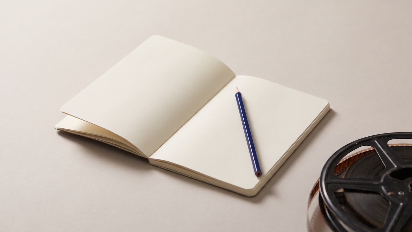 A blank notebook with a pencil and a film reel