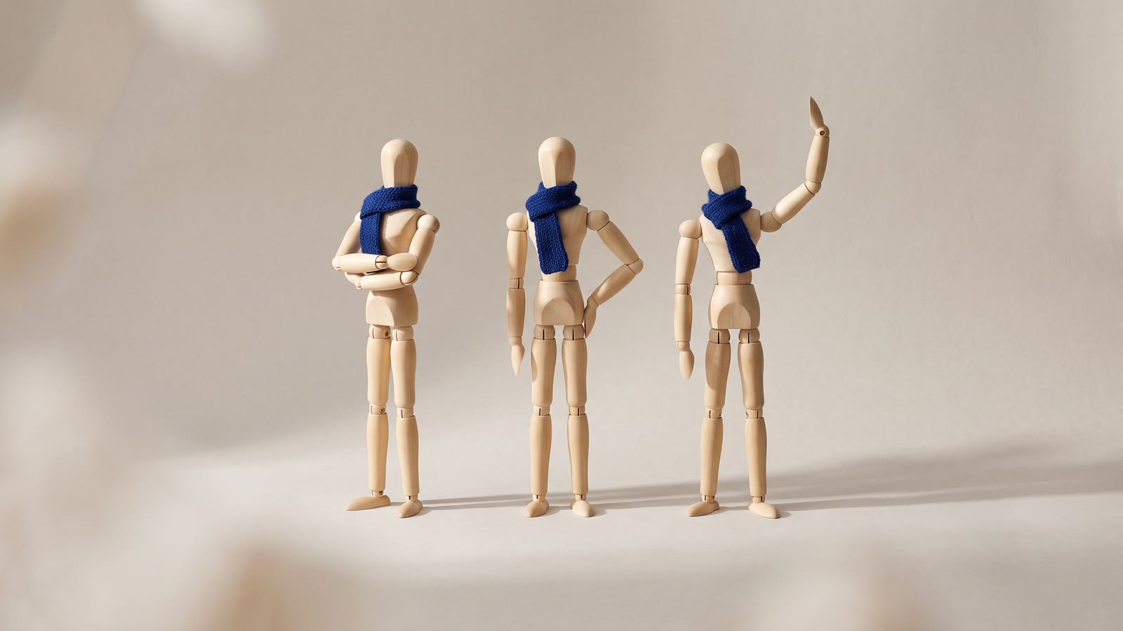 Three identical wooden mannequins in different poses