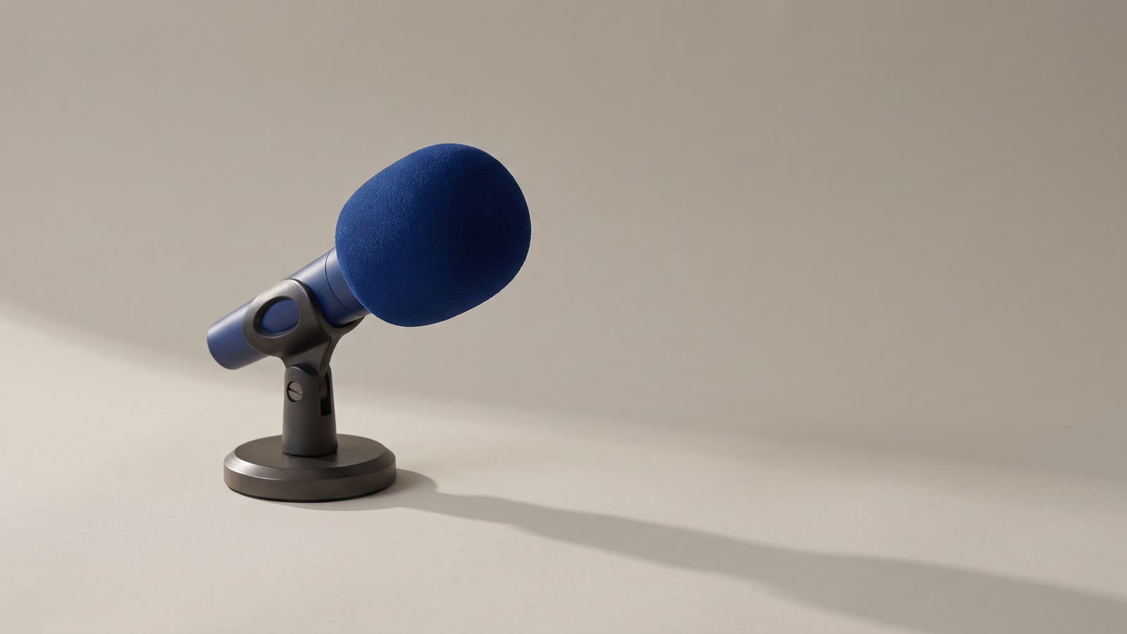 A microphone with a foam windscreen on a small desk stand