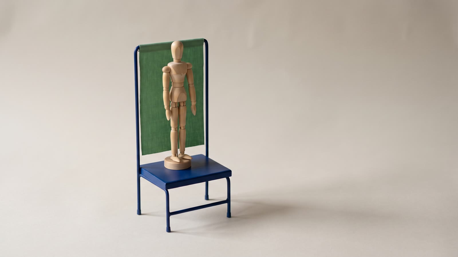 A wooden mannequin standing in front of a miniature green screen