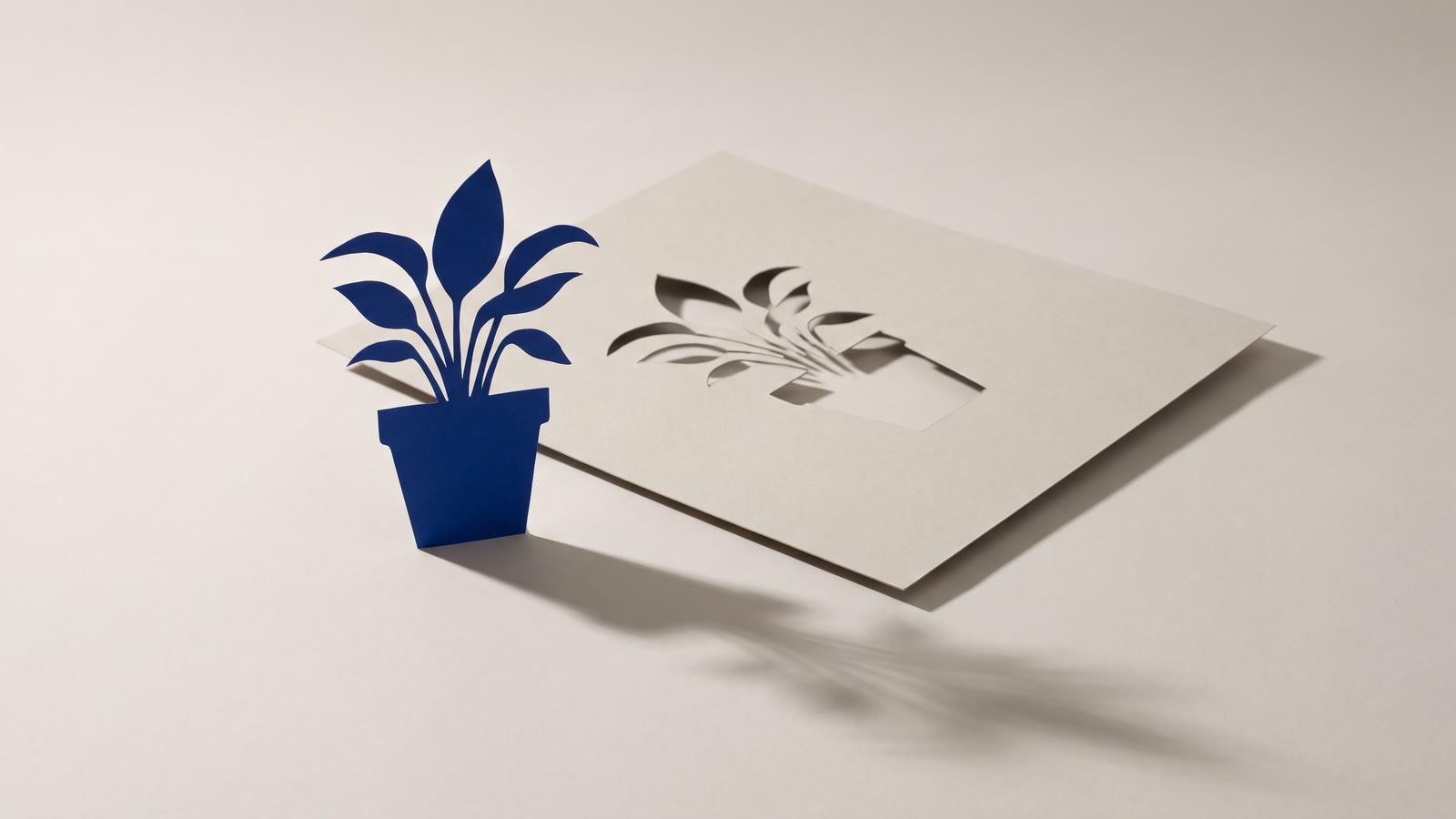 A paper cut-out of a plant standing in front of the sheet it was cut from