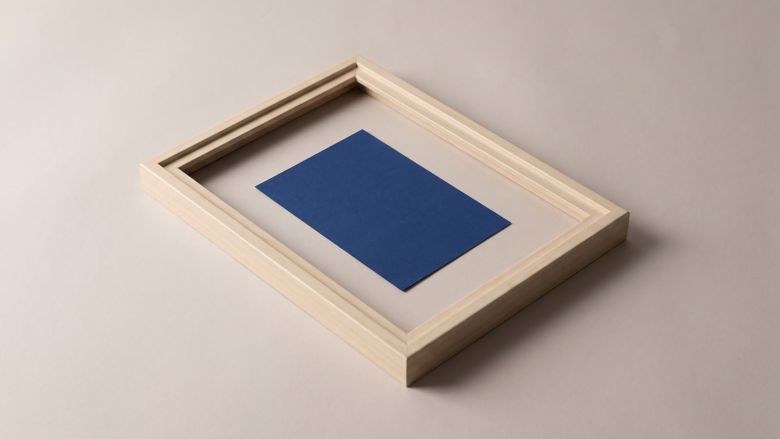 An empty wooden frame lying flat with a small blue paper rectangle placed inside it